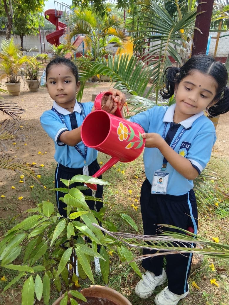 Pre-primary students watering plants on the eco campus at SMHS