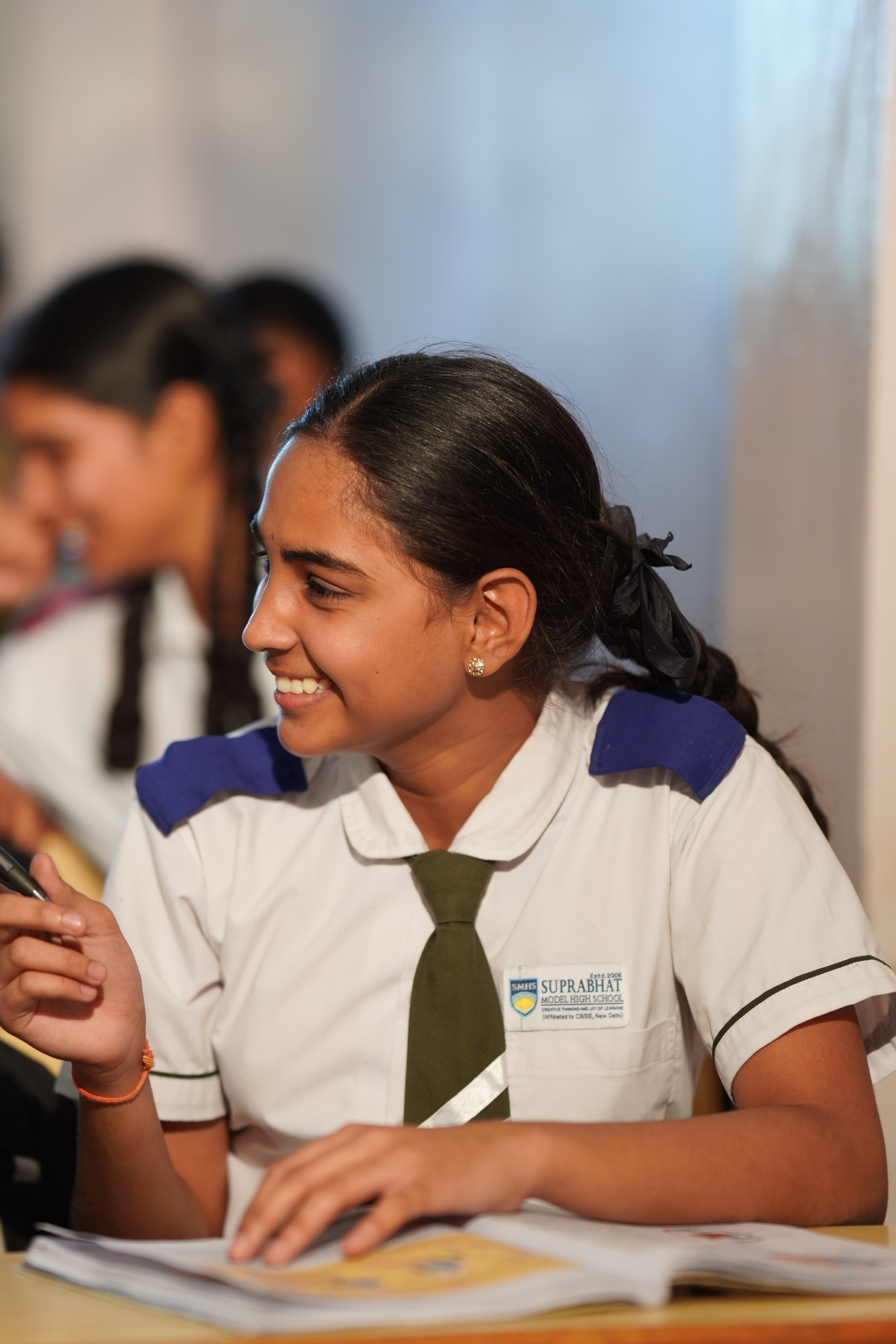 Student in SMHS uniform smiling at desk